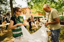 Vrijwilliger en bezoeker maken gaten in oude lakens om te gebruiken als zonwering.
