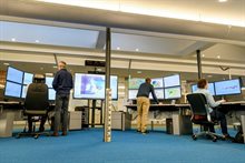 Medewerkers achter meerdere beeldschermen met weerkaarten en meetgrafieken