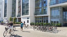 Fietsenstalling bij appartementen met witte muren en lichte tegels in de straat.